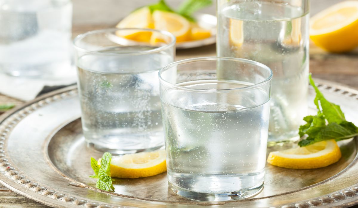 two glasses with mineral water being poured into it and sitting on a tray