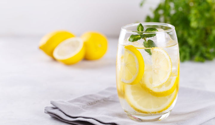 lemon inside glass of water with mint at the top
