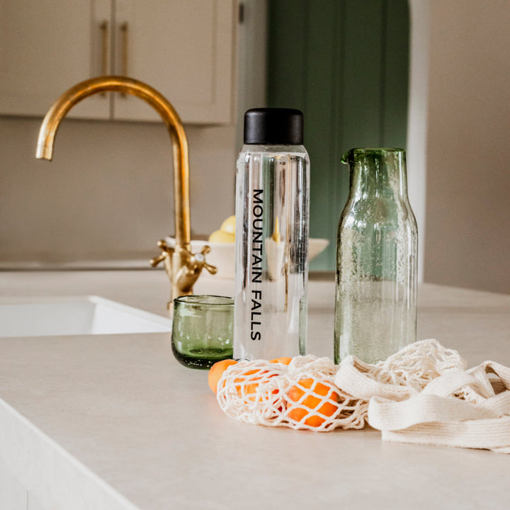 Sparkling Water on a counter with fruit and a glass