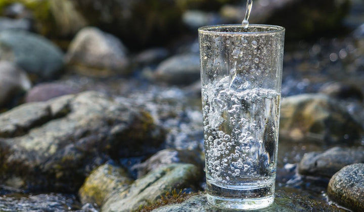 Glass being filled with sparkling water in river